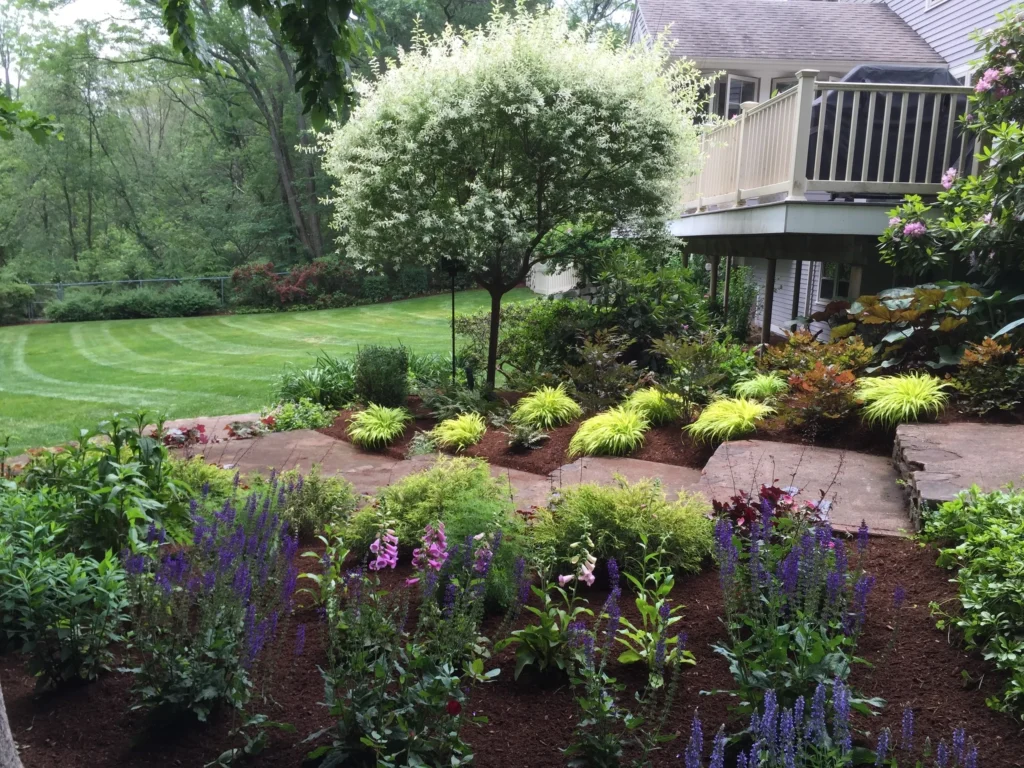 Lush garden with colorful flowers and tree.