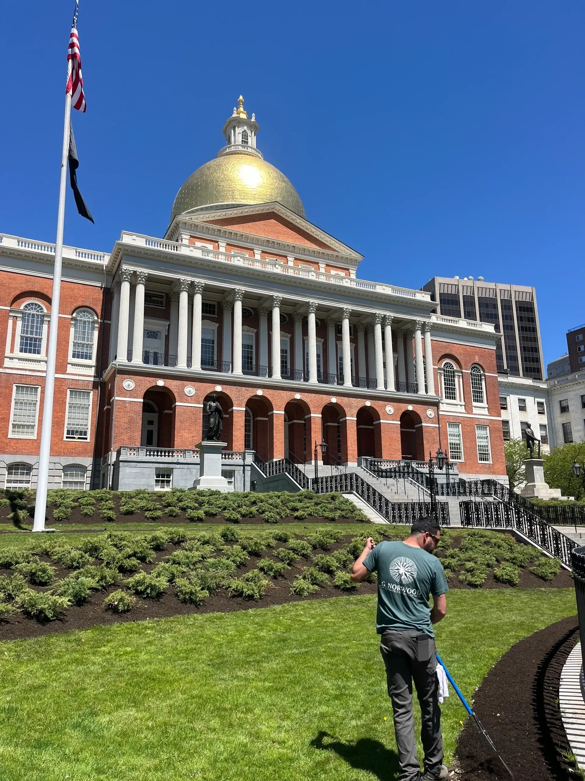 Man mowing lawn near historic building.